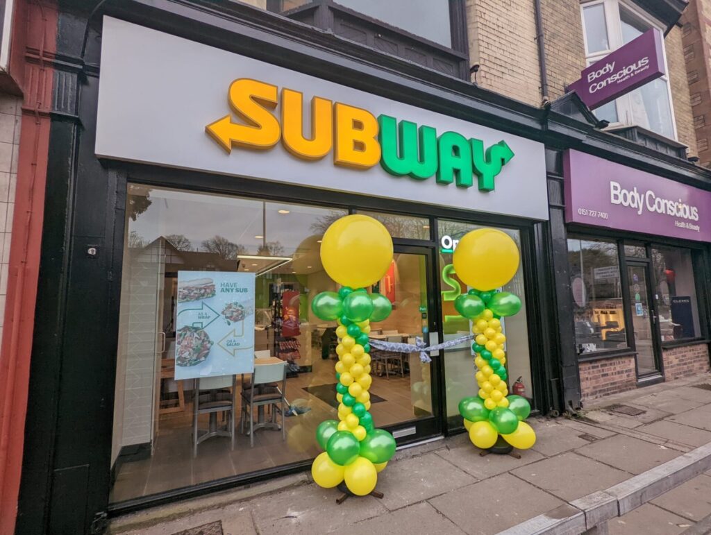 Green and yellow balloon pillars outside Subway
